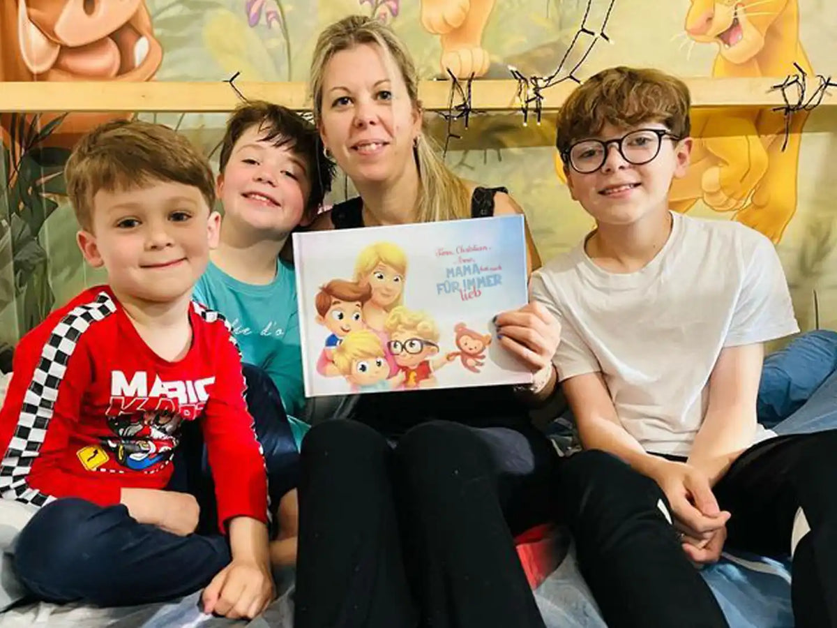 Die Mutter hält ihr kostbares Geschenk in der Hand, ein Buch mit individuellen Figuren von ihr und ihren drei Kindern.	