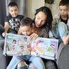 Eine Mutter mit drei Söhnen schauen sich ihr personalisiertes Buch von Hurra Helden. 