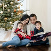 Eine Familie feiert Weihnachten und liest das personalisierte Buch für zwei Kinder von Hurra Helden. 