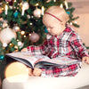 Ein Kleinkind blättert in seinem personalisierten Weihnachtsbuch von Hurra Helden, das voller magischer Geschichten ist.