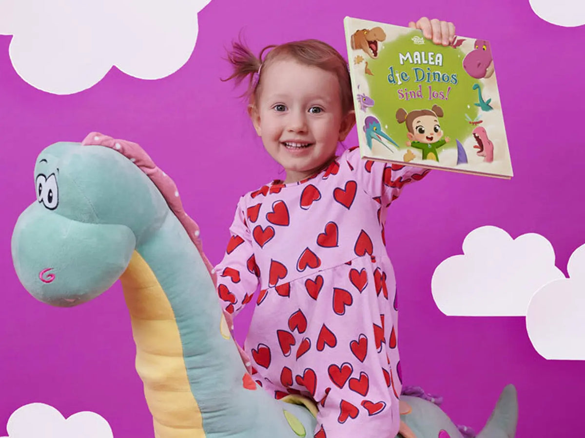 Die kleine Dinosaurierliebhaberin Malea hält ihr neues, tolles personalisiertes Buch über sich und Dinosaurier in der Hand.	