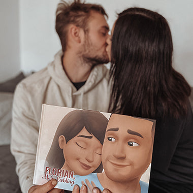 Eine Frau küsst ihren Mann, der ein personalisiertes Buch für Paare in der Hand hält, das beste Geschenk für den Freund.