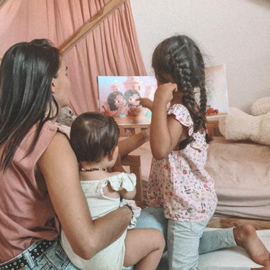Mama und ihre Kinder blättern in ihrem personalisierten Buch „Ein Dreamteam“ für Kinder von Hurra Helden.