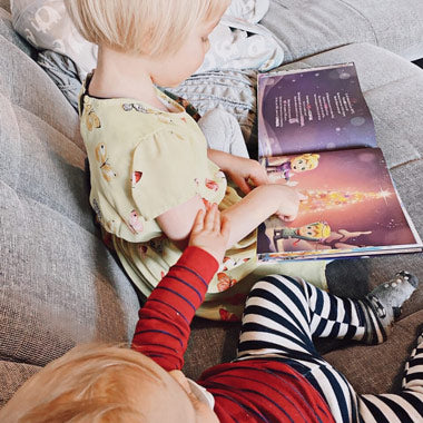 Zwei Kinder blättern in ihrem eigenen personalisierten Hurra-Helden-Buch, das über Weihnachten und ihrer Verbindung handelt.