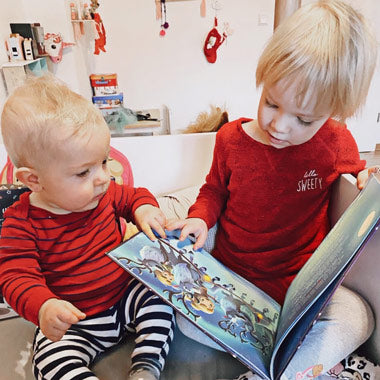 Zwei Kinder lesen eine spannende Weihnachtsgeschichte über Geschwister und deren Zusammenhalt.