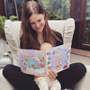 Die kleine Tochter schaut sich das individuelle Buch an, das sie bei ihrer Geburt bekommen hat.		