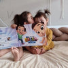 Eine große Schwester küsst ihre kleine Schwester, während sie ihr personalisiertes Buch von den Hurra Helden bestaunen. 