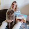 Ein Mädchen hält liebevoll ihren Hund und ist glücklich, weil sie ein personalisiertes Buch für Haustiere geschenkt bekommen hat.