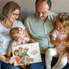 Lachende Großeltern und Enkelkinder die sich über ihr personalisiertes Buch freuen. 