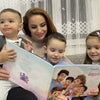 Eine Mutter mit ihren 3 Kindern sitzt auf der Couch und schaut sich das personalisierte Buch für Familien an. 