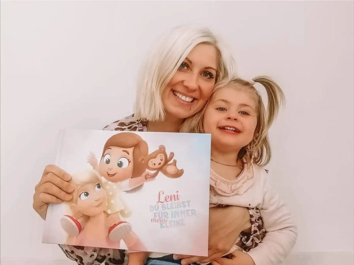Die Mutter und das Mädchen lächeln, als sie ihr neues selbstgemachtes Erinnerungsbuch für die Mutter in der Hand halten.