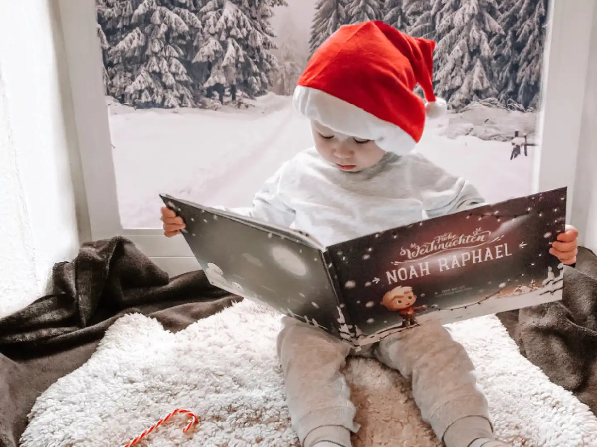 Ein Kind mit Weihnachtsmütze liest sein persönliches Buch, das schönste Geschenk zu Weihnachten.  