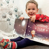 Ein Kind freut sich über sein personalisiertes Buch zu Weihnachten von Hurra Helden. 