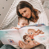 Das hübsche Mädchen hält ein besonderes Geschenk für die Mutter in der Hand, ein personalisiertes Buch für Mutter und Tochter.