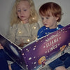 Ein Bruder und Schwester lesen ihr personalisiertes Buch zu Weihnachten von Hurra Helden.