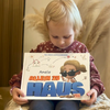 Ein kleines Mädchen hält ihr neues personalisiertes Buch „Allein zu Haus“ in der Hand.
