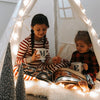 Zwei Geschwister haben es sich gemütlich gemacht und lesen aus ihrem eigenen personalisierten Weihnachtsbuch für zwei Kinder.