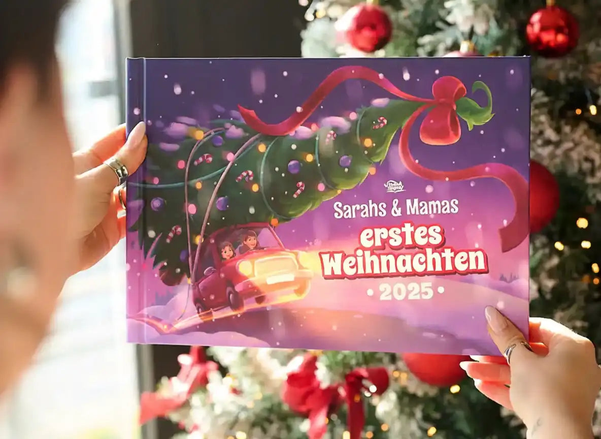 Person hält das Weihnachtsbuch „Sarahs & Mamas – Erstes Weihnachten 2025“ vor einem geschmückten Tannenbaum.