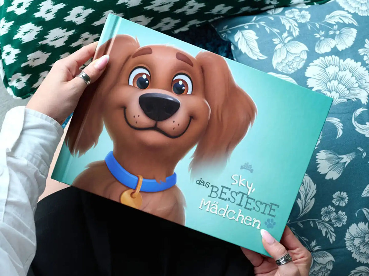 Person hält das Hundebuch 'Sky das BESTESTE Mädchen' mit einem niedlichen Cartoonhund auf dem Cover.